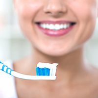 Smiling woman with toothpaste on toothbrush