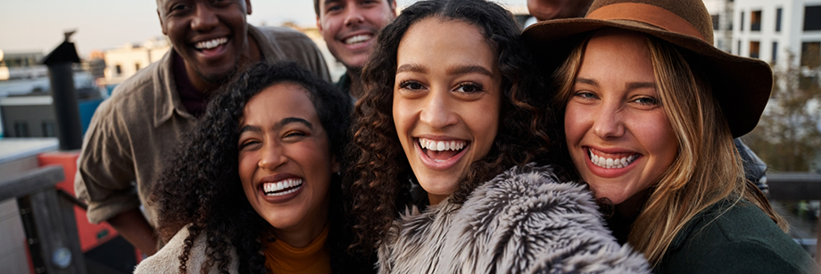 Group selfie of several adults on a city street at sunset